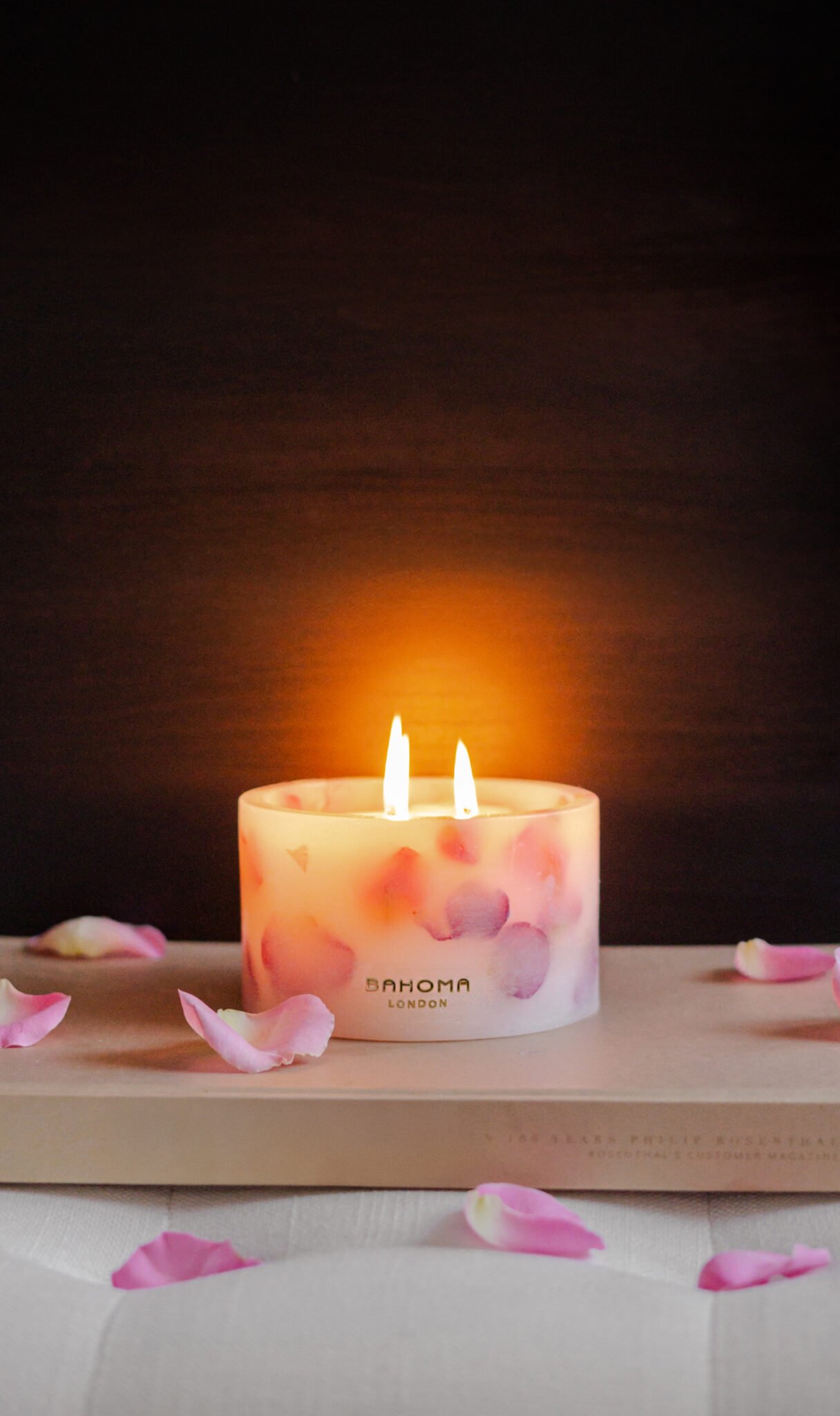 Lit up Velvet Rose - Small Pillar Candle made with real rose petals held in hand on a dark moody background with a glow