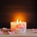 Lit up Velvet Rose - Small Pillar Candle made with real rose petals held in hand on a dark moody background with a glow