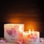 Lit up Velvet Rose - Small Pillar Candle made with real rose petals on a dark moody background with a glow, accompanied by a Grand pillar in same design