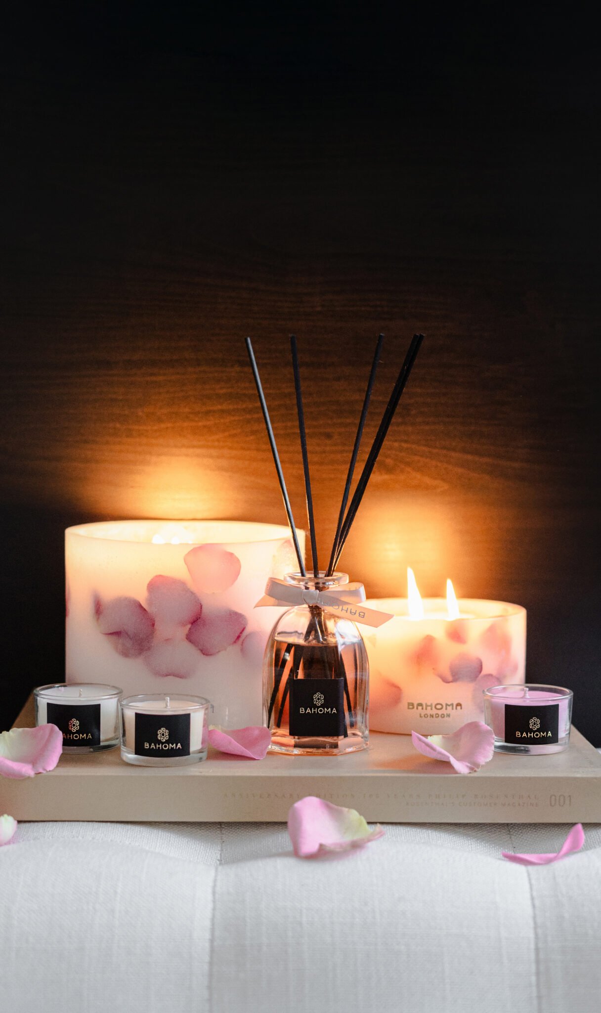 Velvet Rose Botanical Pillar candles made with real rose petals, octagonal diffuser and mini candles in a romantic display with dark background and glow