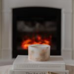 Cherry Blossom Scented Grand Pillar Candle on a white book with dried real cherry blossom petals in front of fire place in lifestyle setting