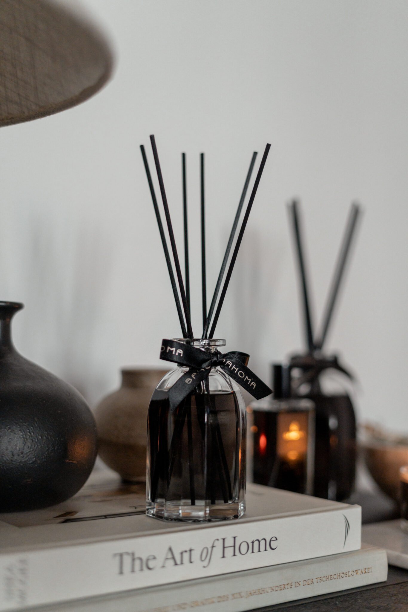 Bahoma Obsidian Collection 100ml fragranced octagonal diffuser with black liquid and black reeds styled on books in a modern interior