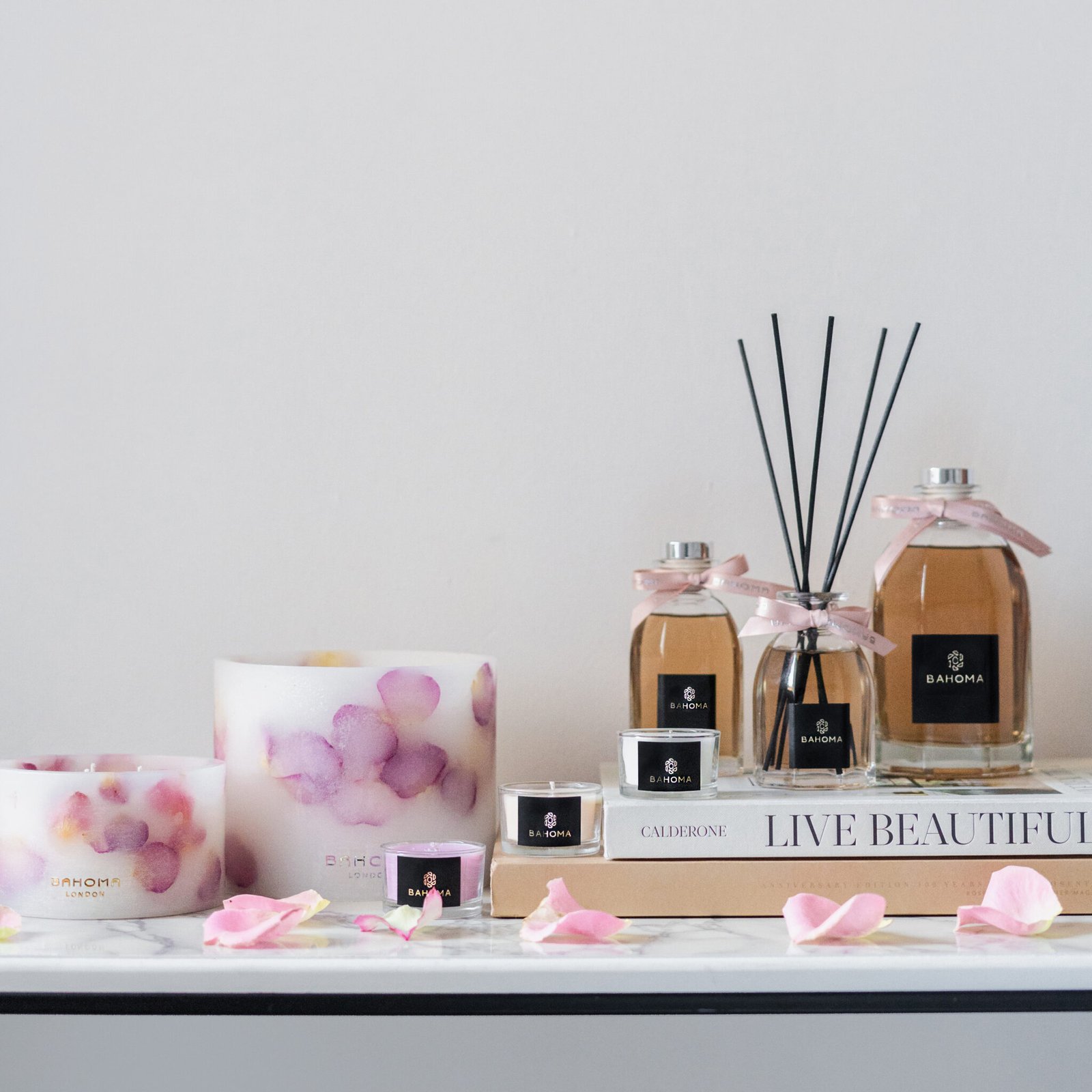 500ml Fragranced Octagonal Diffuser in a gift box - Velvet Rose - Full collection in Velver Rose Fragrance arranged on a side table. diffusers are raised and candles are displayed just next to the bottles