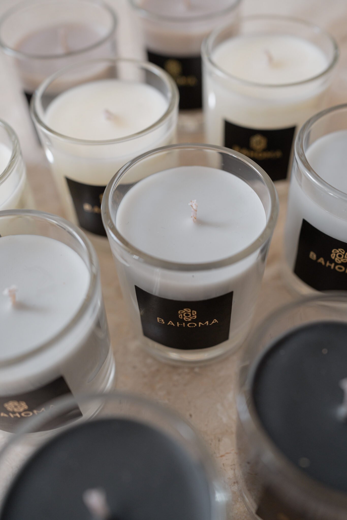 Close-up assortment of Bahoma travel candles in white, black, and taupe wax; high-quality scented candle gift set collection.